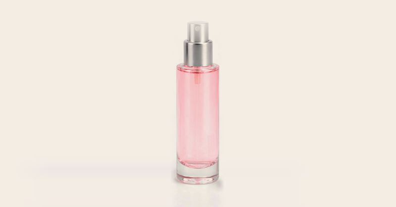 Rosa sprayflaska i glas mot ljus bakgrund
